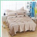 The cooling blanket in camel on a bed in a bedroom.