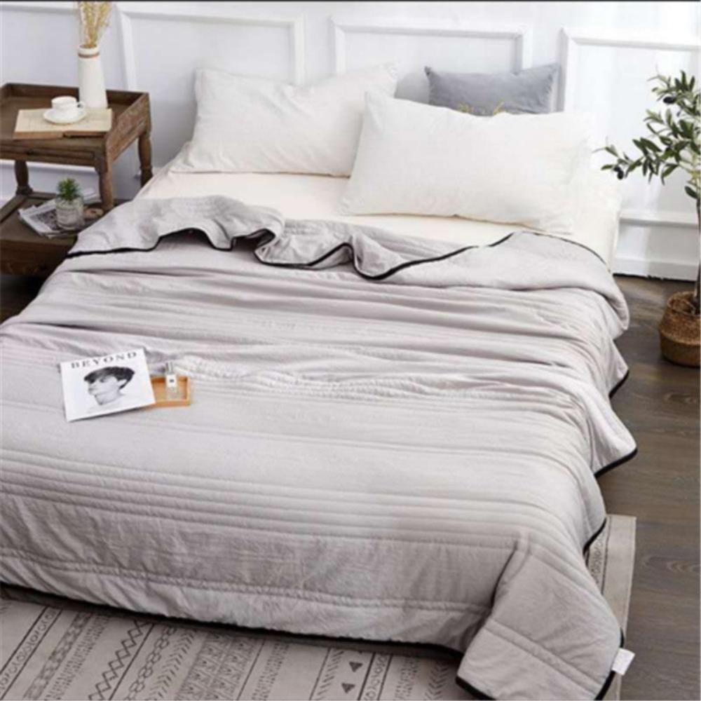 The cooling blanket in grey on a bed in a bedroom.