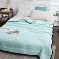 The cooling blanket in jade green on a bed in a bedroom.