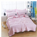 The cooling blanket in pink on a bed in a bedroom.