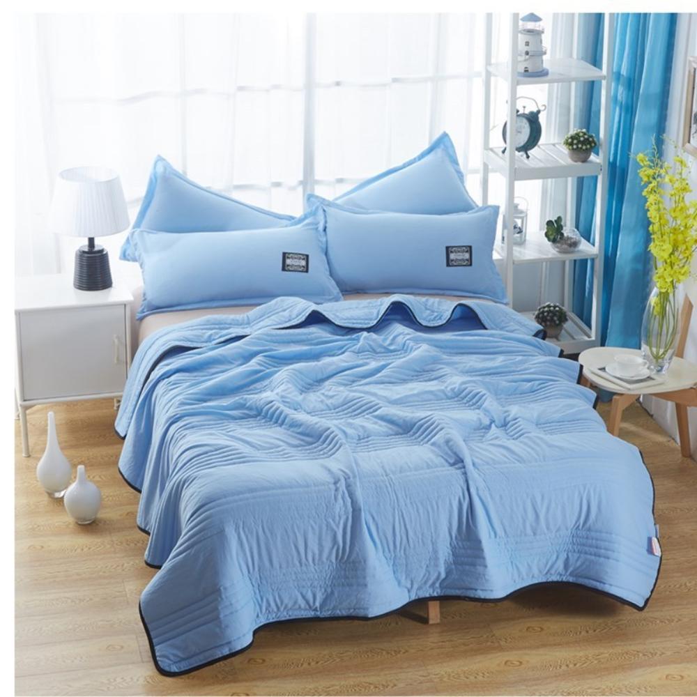 The cooling blanket in sky blue on a bed in a bedroom.