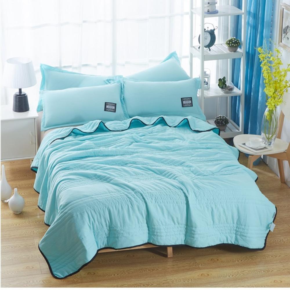 The cooling blanket in water green on a bed in a bedroom.