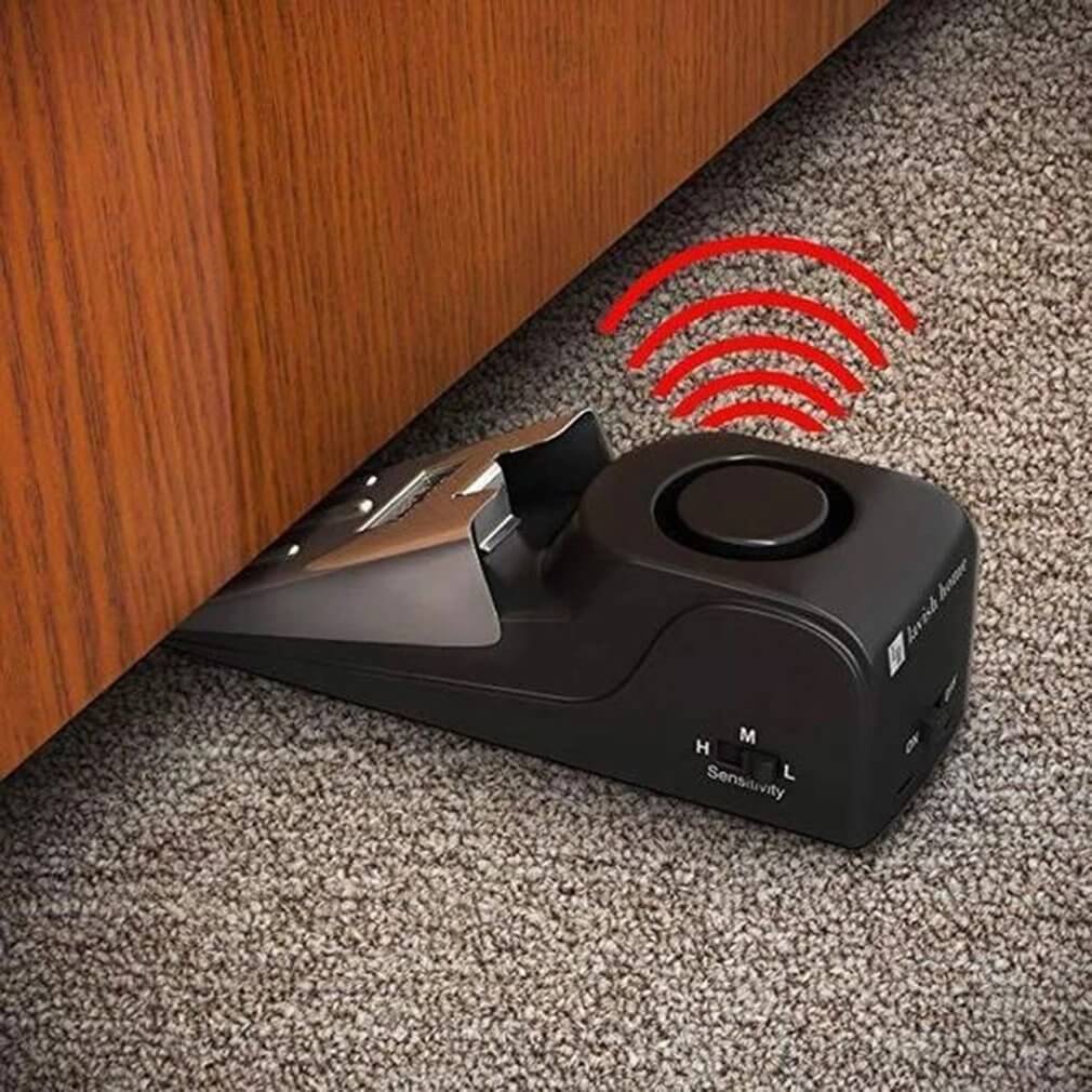 The door stop alarm wedged under a door, pulses coming from the device showing its alarm decibel sensitivity.