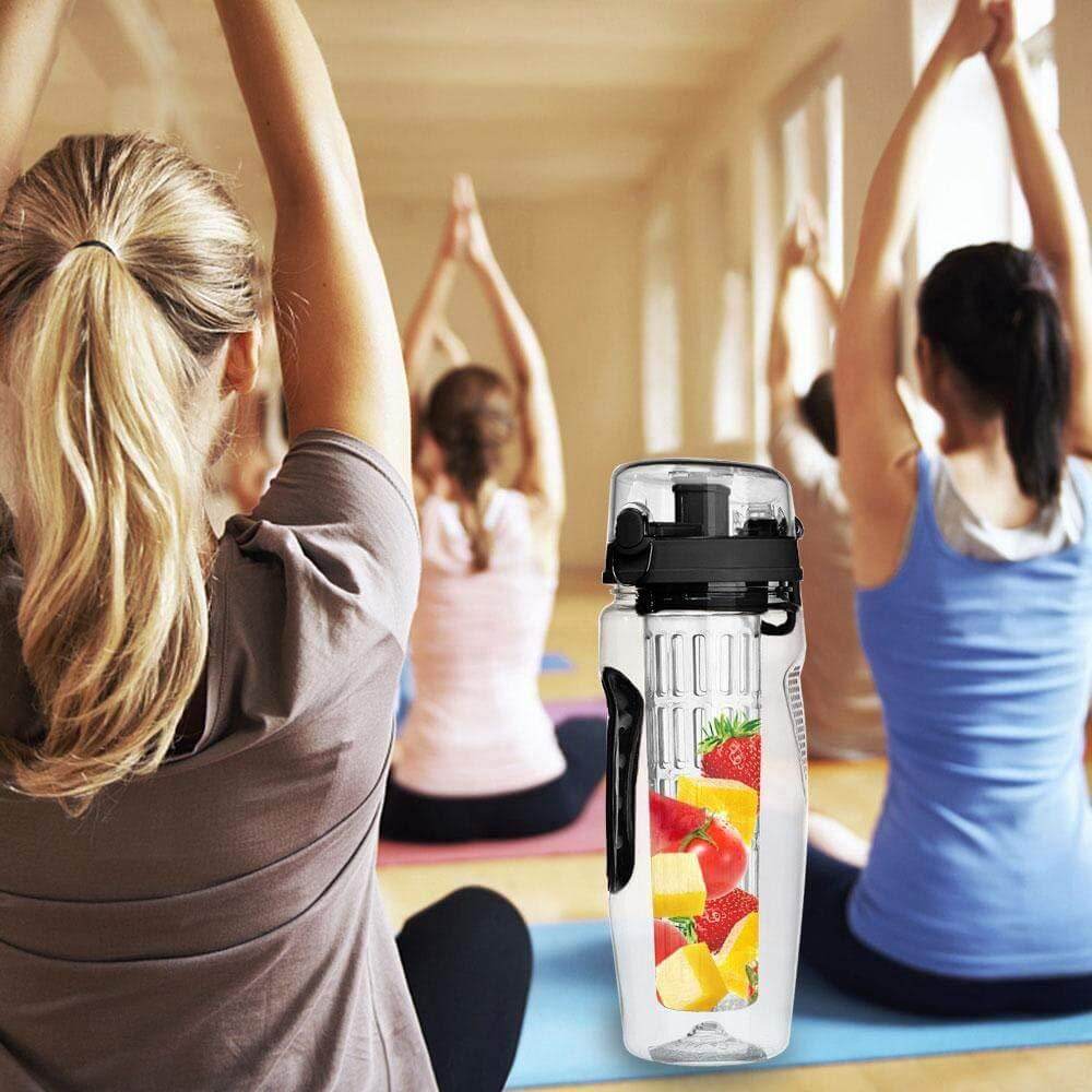 The fruit infuse water bottle in black containing various fruits. A room full of women doing yoga.